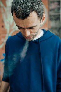 Close-up of man wearing sunglasses standing against blue wall