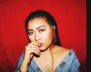 Portrait of young woman against red background