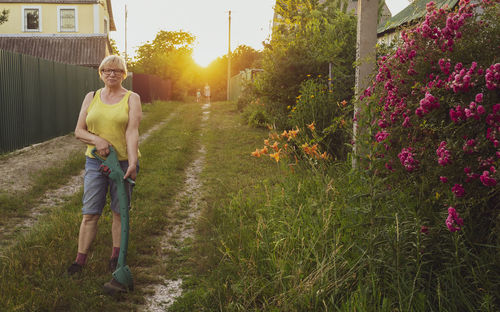 Full length of woman holding metal detector while standing on field