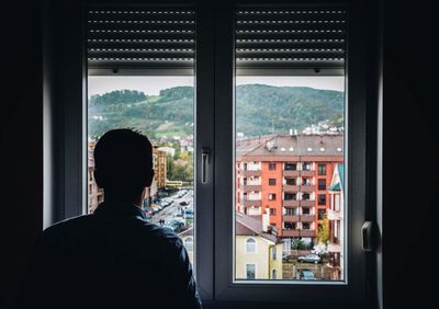 Rear view of man looking through window