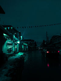 Cars on illuminated street amidst buildings at night