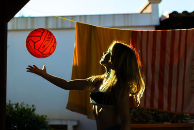 Side view of young woman playing with ball at balcony