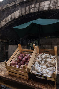 Onions and garlic bulbs in crates for sale at market stall