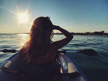 Rear view of woman in boat against sky during sunset