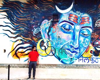 Full length of man standing against graffiti in city