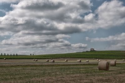 Hay bales on field against sky