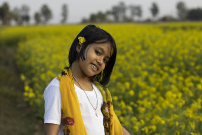 Portrait of a smiling young woman standing on field