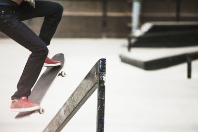 Low section of man performing skateboard stunt at skateboard park