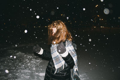 Playful woman during snowfall at night