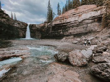 To women hiking on rock formations near waterfall at crescent falls, alberta 