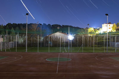 Illuminated soccer field against sky at night