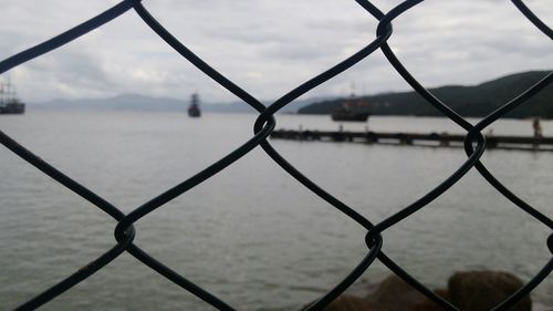 Close-up of chainlink fence against lake