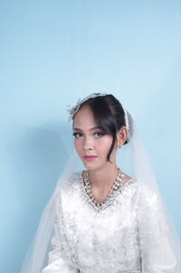 Portrait of bride standing against wall