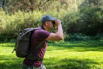 Hiker in the woods lurking in search of wildlife. man with binoculars peers into the distance look