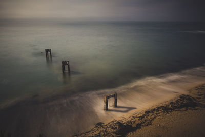 High angle view of wooden post on beach against sky