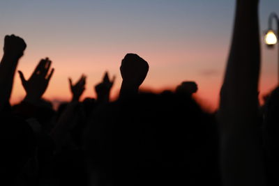 Silhouette people at music concert against sky during sunset