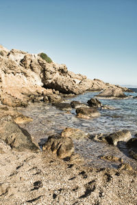 Rock formations in sea against clear sky