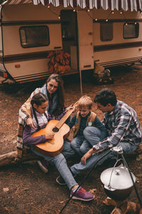 Happy family on camping trip relaxing in the autumn forest camper trailer. fall season outdoors trip