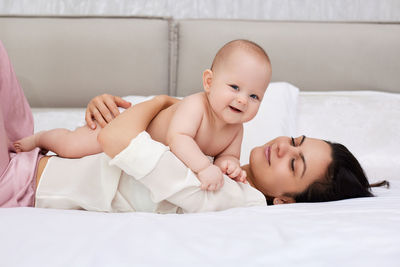 Portrait of smiling mother and daughter lying on bed at home