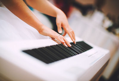 Cropped hands of woman playing piano