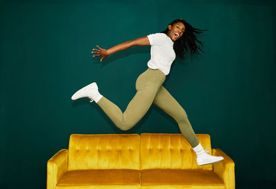 Young black student jumping over a yellow coach.