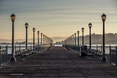 Walkway by railing against sky