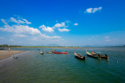 Boats moored in sea against blue sky