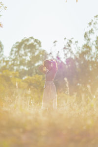 Side view of woman standing on field against sky