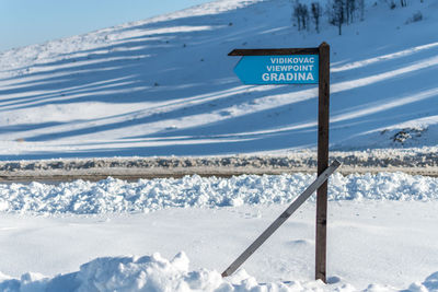 Road sign on snow covered land