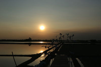 Silhouette pier over sea against sky during sunset