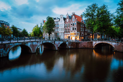 Bridge over river in city against sky