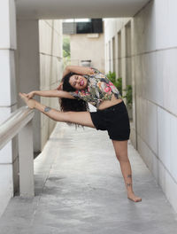 Full length of woman stretching in corridor