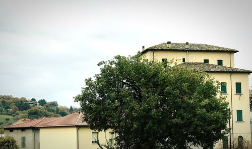 High section of building and trees against sky