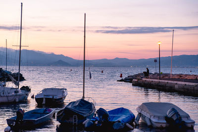 Sailboats moored on sea against sky during sunset