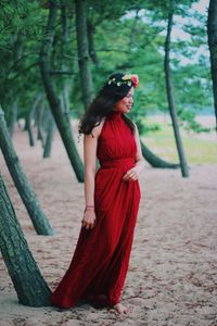 Side view of young woman standing by tree