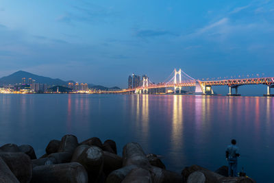 Illuminated bridge over sea against sky at dusk