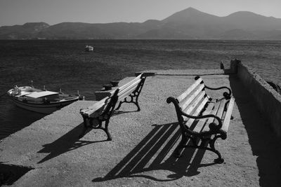 Deck chairs on shore by lake against sky