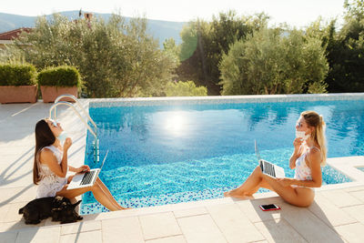 Portrait of young woman sitting at poolside