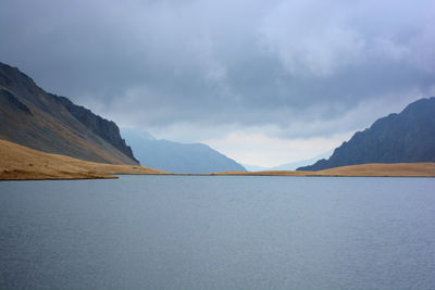 Scenic view of lake by mountains against sky