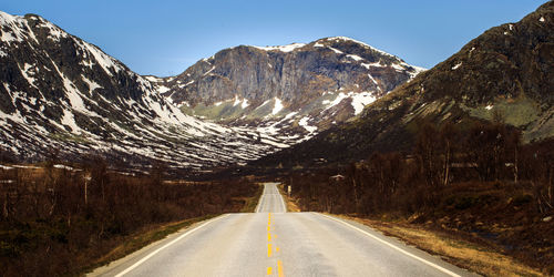 Road amidst snowcapped mountains against sky