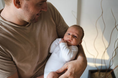 Portrait of adult man holding newborn baby boy 