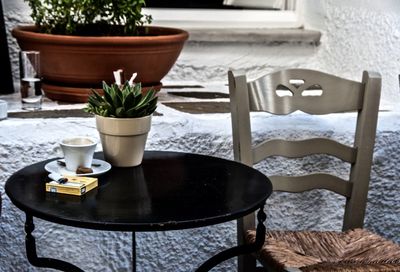 Potted plant with coffee cup on table by chair