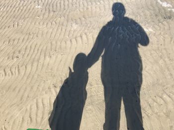 Shadow of people on sand at beach