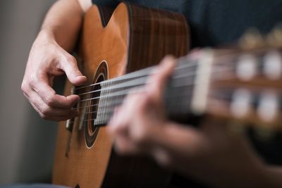 Midsection of man playing guitar