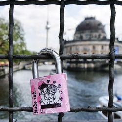 Close-up of padlocks hanging on railing against bridge