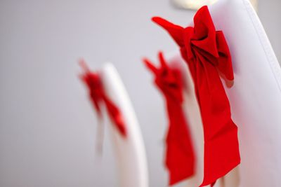 Close-up of red tied bows on white chair