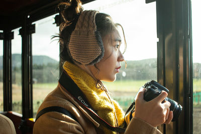 Portrait of woman photographing through window