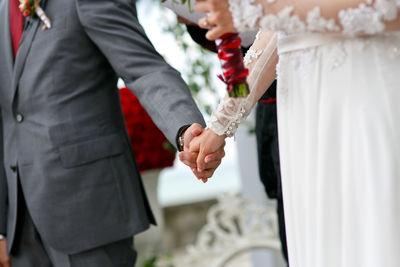 Midsection of newlywed couple holding hands