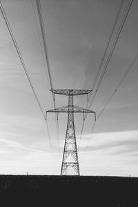 Low angle view of electricity pylon on field