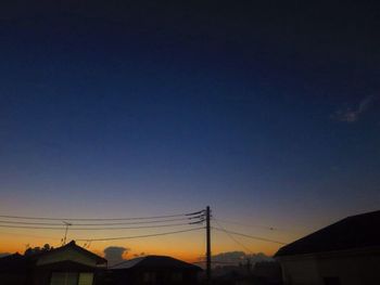 Low angle view of silhouette electricity pylon against clear sky